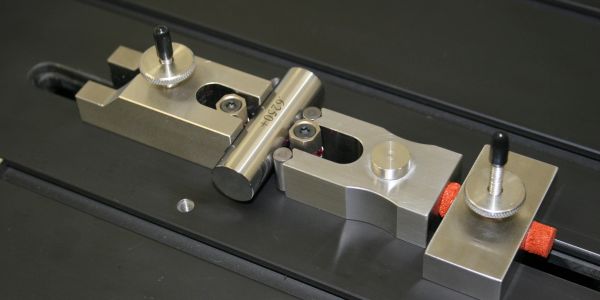 Precision metal tool with adjustable screws on black surface.