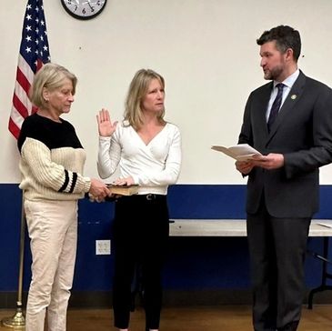 A woman takes an oath in a formal ceremony with two other individuals.