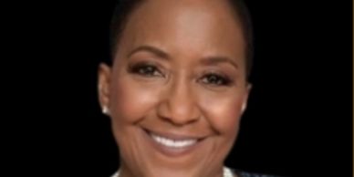 Close-up of a smiling woman against a black background.