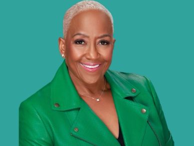 Smiling woman in green jacket with short blonde hair.