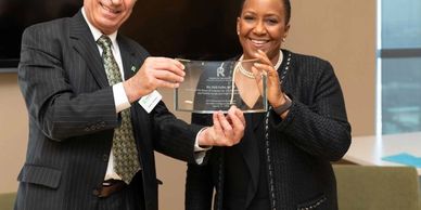 Two people holding a glass award plaque.