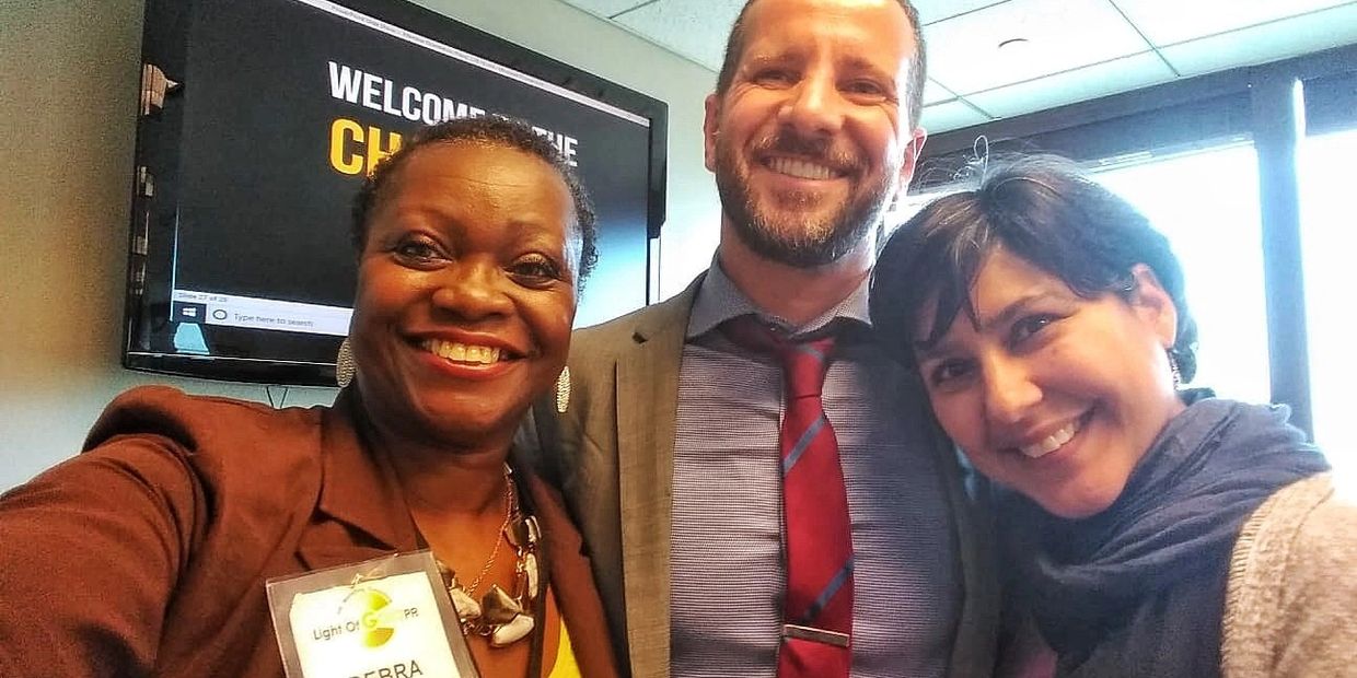Three people smiling for a cheerful group selfie indoors.