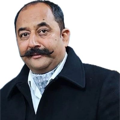 Man with a styled mustache wearing a black coat and patterned scarf.