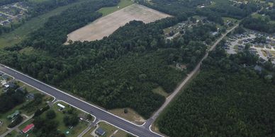 Aerial view of a forested area bordered by roads and some residential buildings.