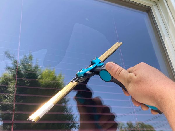 Window squeegee being used in a traditional window washing style