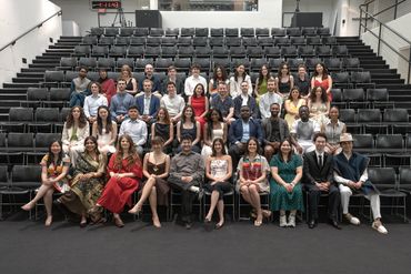 A large group photo of diverse young adults in an auditorium.