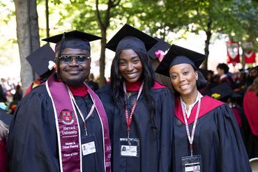 Three graduates in academic gowns and caps.