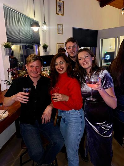 Group of 4 people dressed up for a party and drinking cocktails.