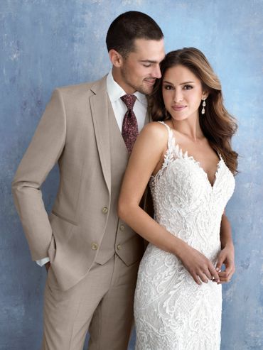 A couple dressed in wedding attire posing against a blue background.