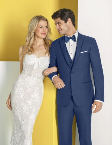 Elegant couple in wedding attire posing against a yellow and white background.