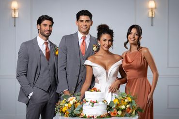 Four people dressed elegantly around a wedding cake, smiling.