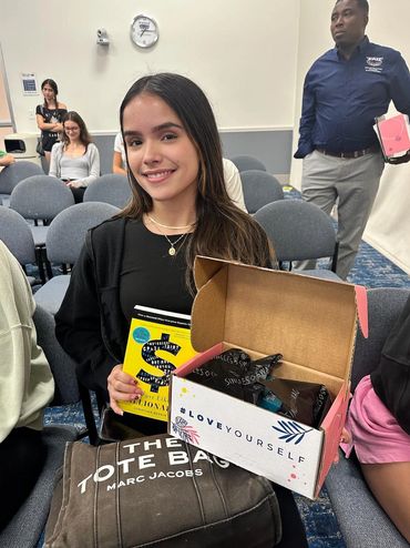 Girl holding free AMA merchandise (a book and a goodie box) at an AMA meeting.