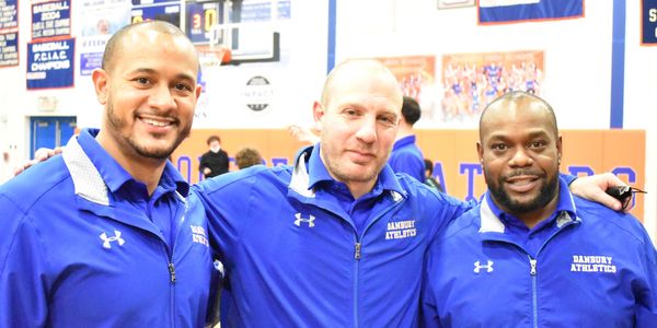 Three men in blue Danbury Athletics jackets posing indoors.