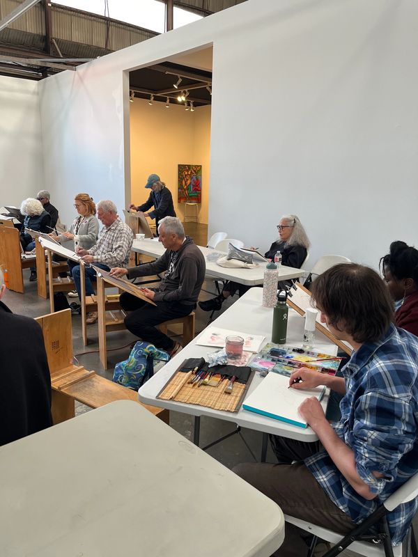 Group of people engaged in a drawing class in a spacious studio.