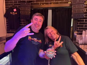 Two smiling people making rock hand signs.