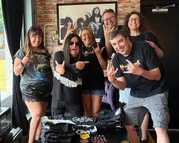 Group of six people posing with rock hand signs and smiles.