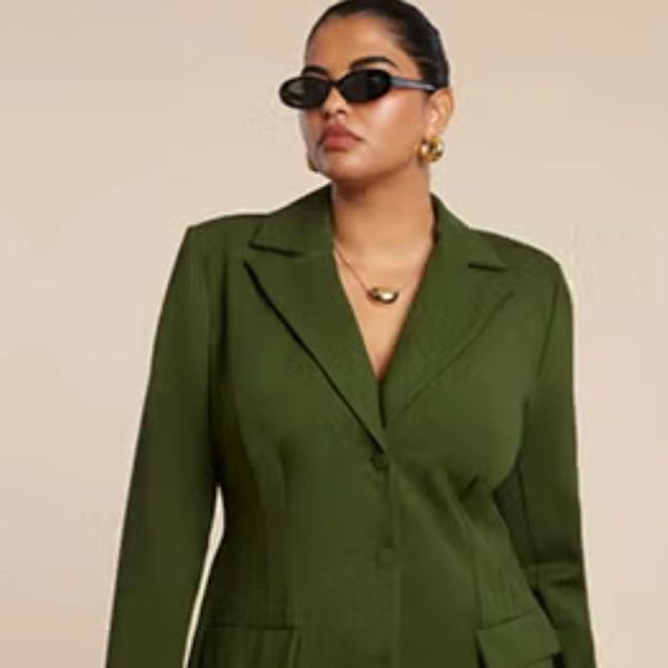 Woman wearing an olive green blazer with black sunglasses and gold accessories.