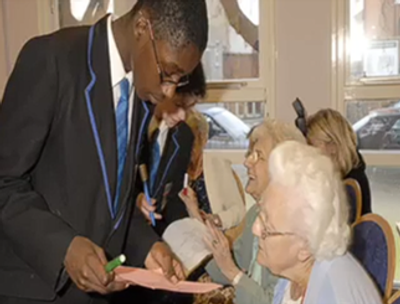 Student helping elderly woman with paperwork.
