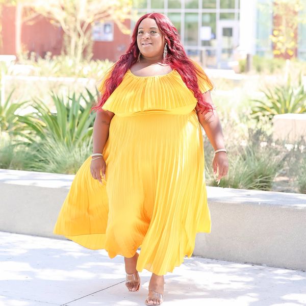 Woman in a flowing yellow dress walking outdoors.