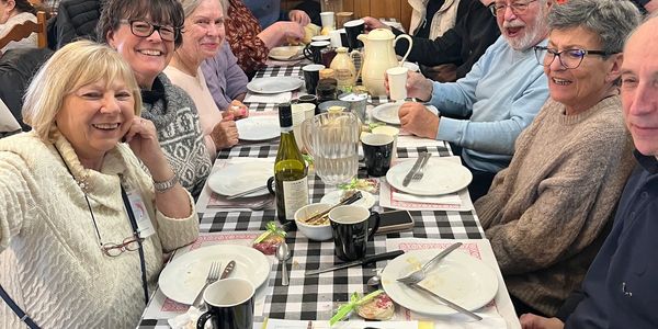 Group of elderly friends enjoying a meal together at a checkered table.