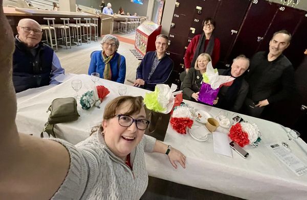 A group of people smiling and taking a selfie around a decorated table.