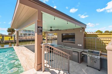 Covered outdoor kitchen pavilion with BBQ grill and bar counter at Serenity Cove