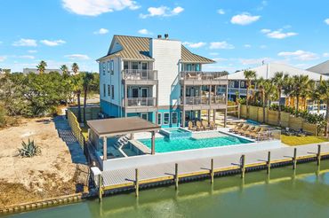 Waterfront perspective of 3-story beach house and swimming pool at Serenity Cove FL