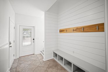 First floor foyer mudroom entryway with bench storage at Serenity Cove Perdido Key
