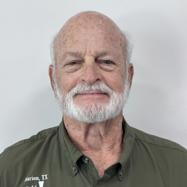 Elderly man with white beard wearing an olive green shirt.