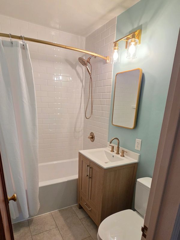 Modern bathroom with blue walls and gold fixtures.