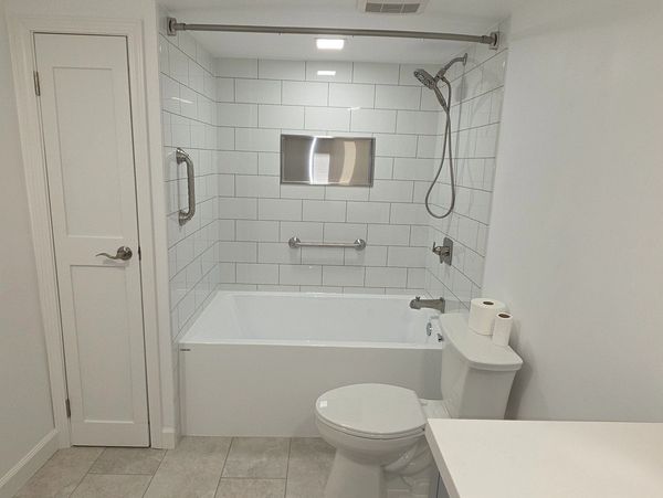 Modern white bathroom with bathtub, shower, and toilet.