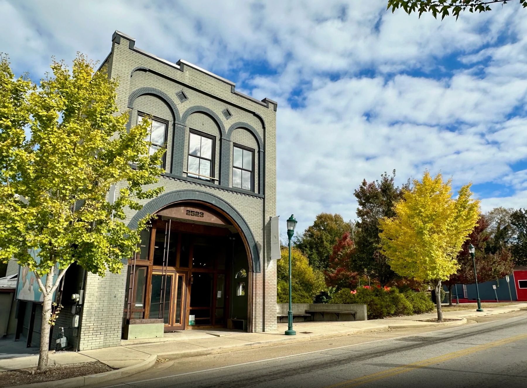 Historic brick building with arched entrance and vibrant fall foliage.
