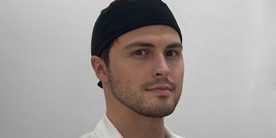 Portrait of a man wearing a black headband and white shirt.