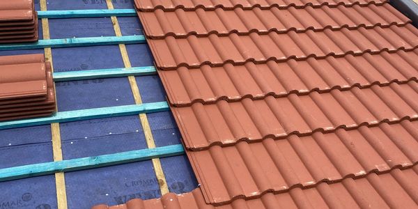 Tiled roof under repair, showing membrane, preparation and red tiles