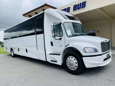 A large white passenger bus parked outside a building with tinted windows.