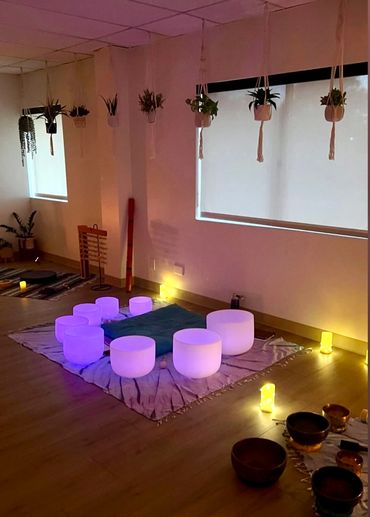 A cozy meditation room with glowing bowls and hanging plants.