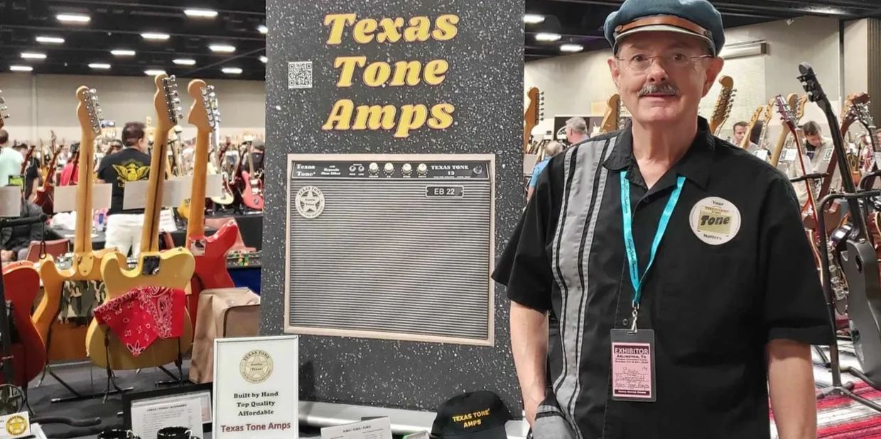 Man stands at Texas Tone Amps booth surrounded by guitars and amps.
