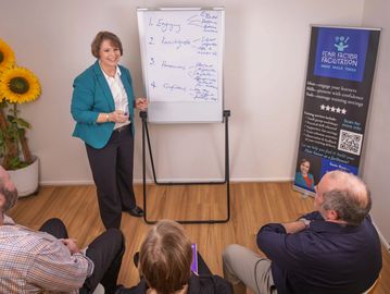 A woman presents a business workshop to a small group in a casual setting.