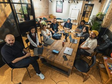 A diverse team gathered around a wooden table in a modern office.