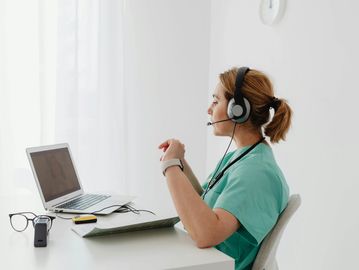 Healthcare professional consulting via video call with headset.