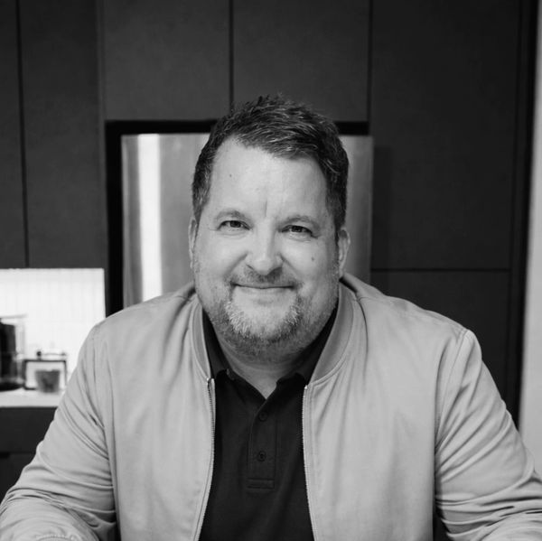 Smiling man in casual jacket sitting indoors.