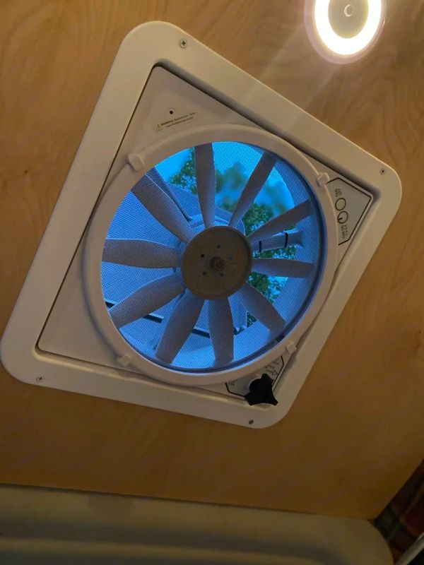 Ceiling-mounted ventilation fan with a view of trees outside.