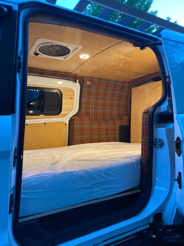 Cozy van interior with a comfortable bed and plaid fabric accents.