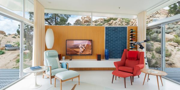 Bright modern living room with large windows and comfortable chairs overlooking desert rocks.