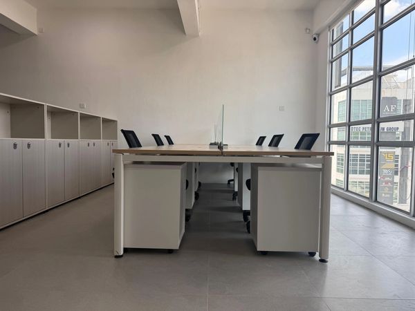 Modern office space with desks, chairs, and large windows for natural light.