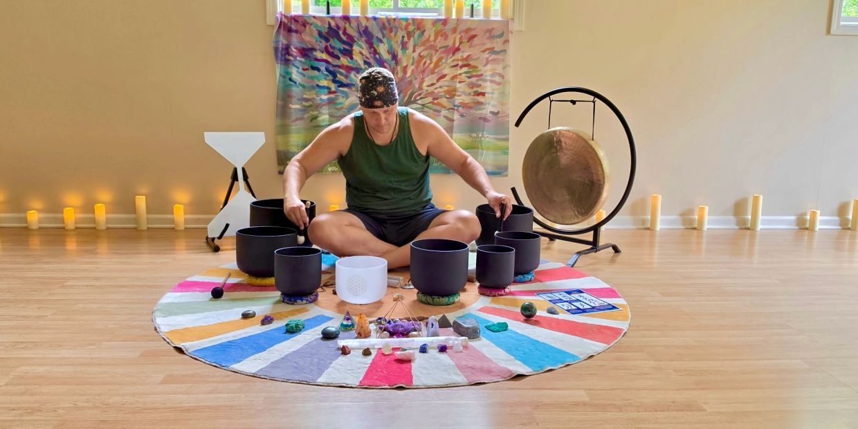 Person playing singing bowls in a serene room.