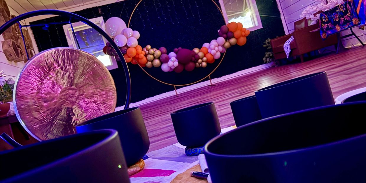Meditative space with singing bowls, a gong, and balloon decor.