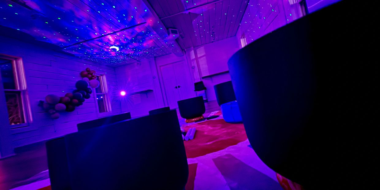 Room with purple lighting, starry ceiling, and scattered chairs.