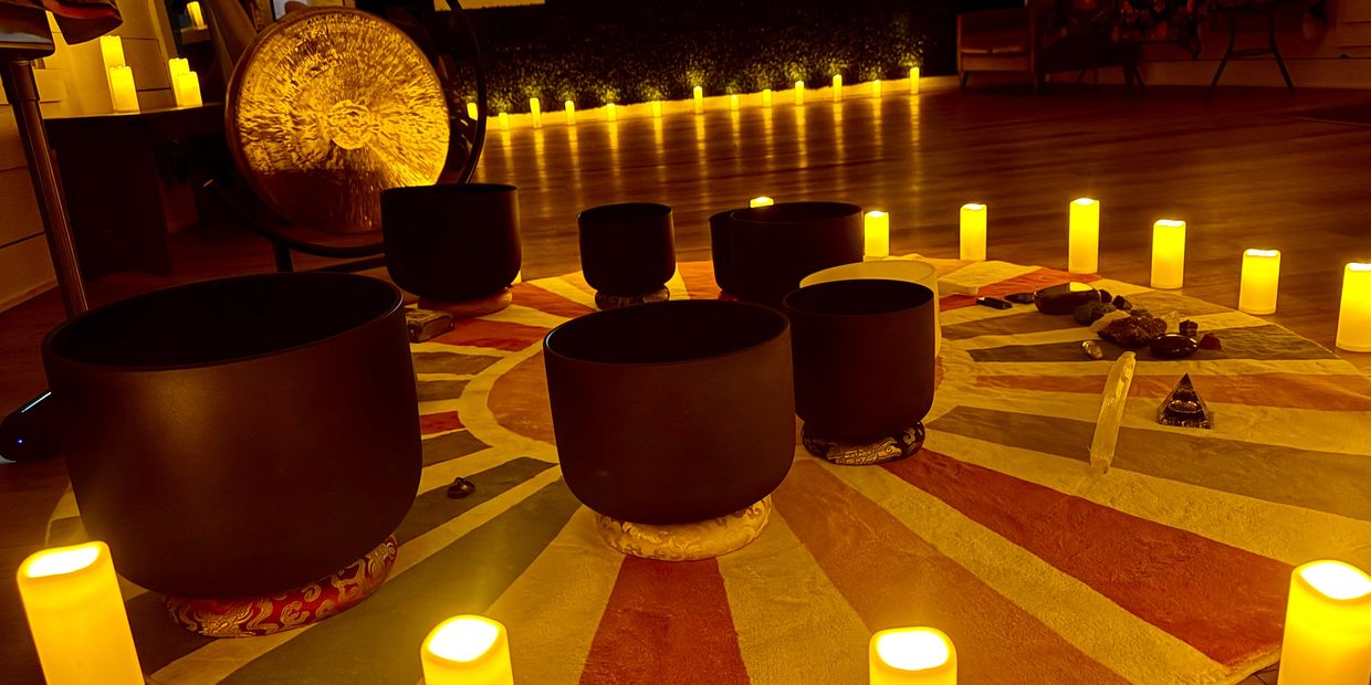 Meditative space with singing bowls and glowing candles arranged in a circle.