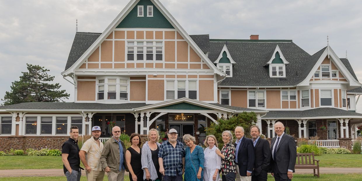 Group of people standing in front of a large vintage house.